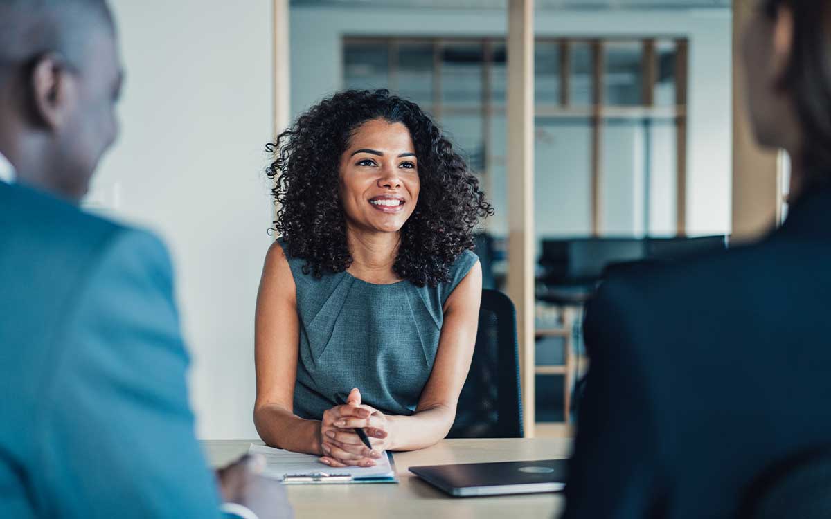 Business woman at a desk talking to two people