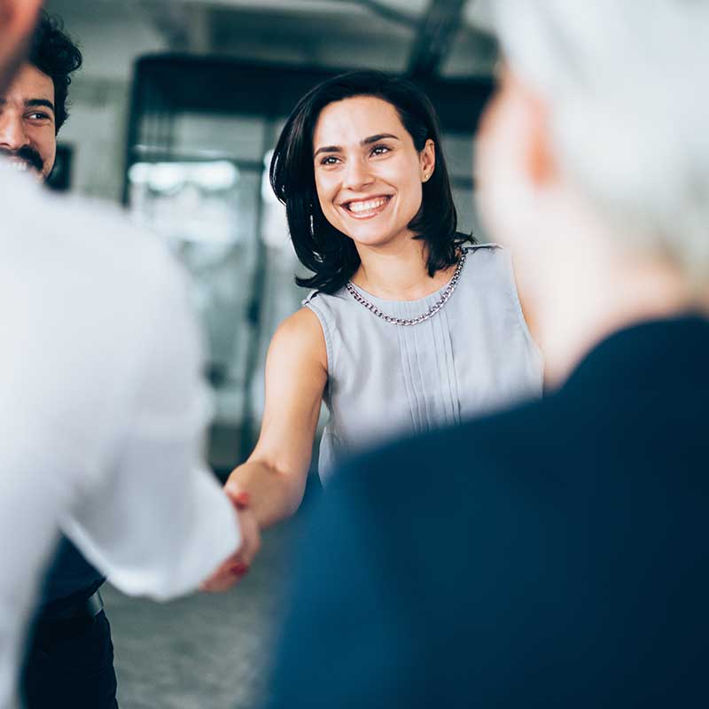 A Woman Smiling and Shaking Another Persons Hand