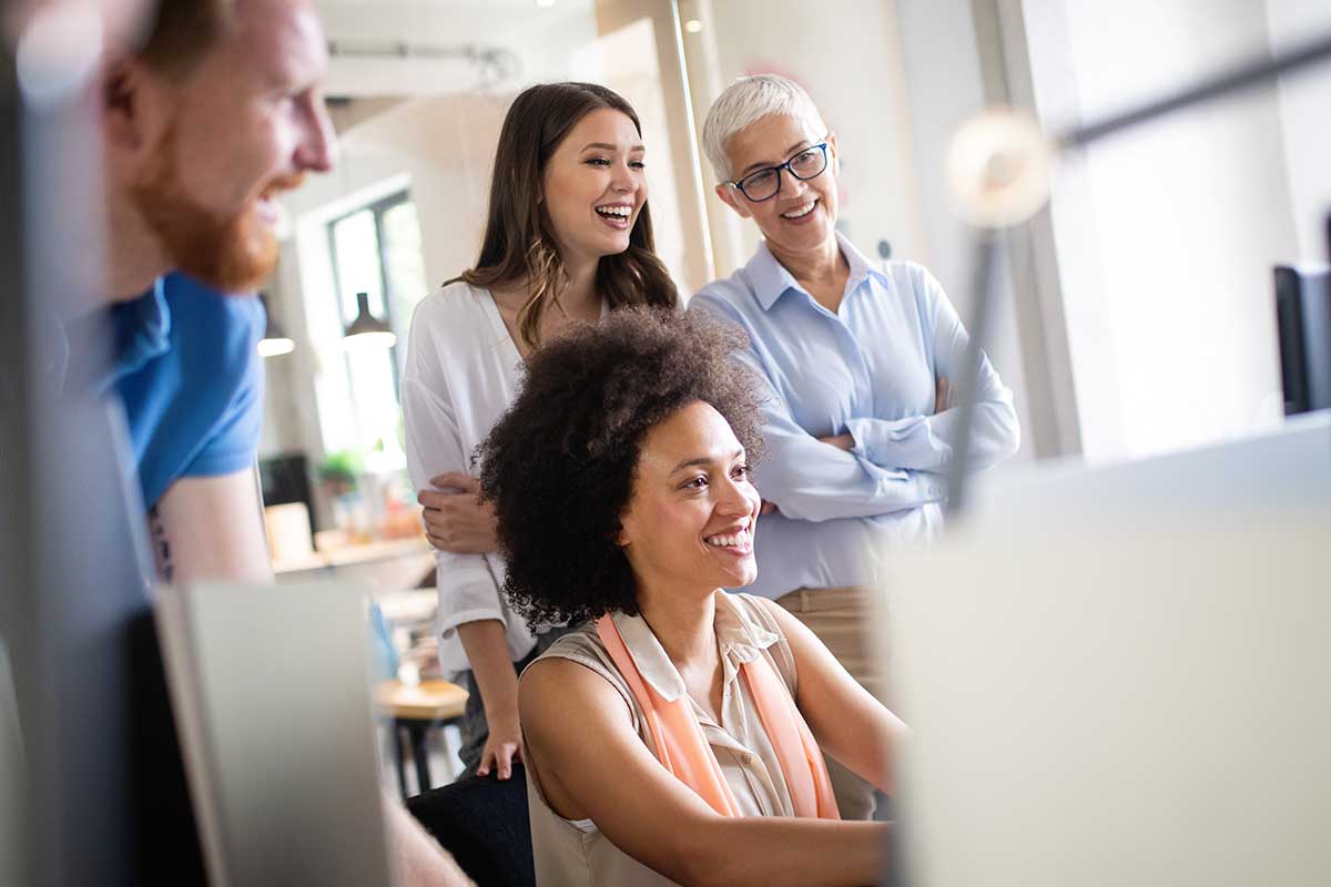 Four People Looking at a Computer Screen and Smiling