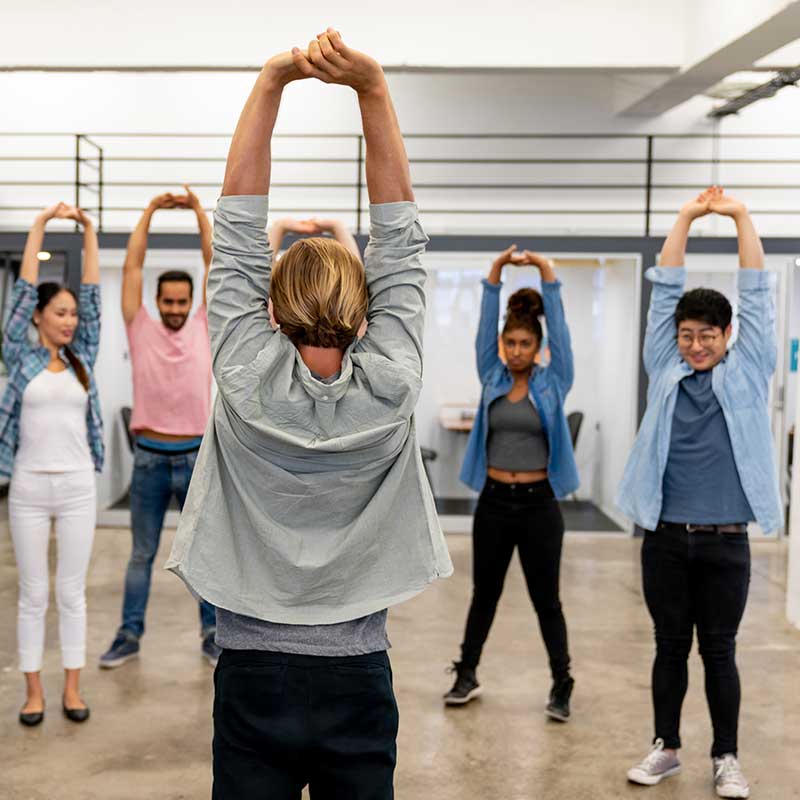 Five People Stretching Upwards With Their Hands in a Gym Studio